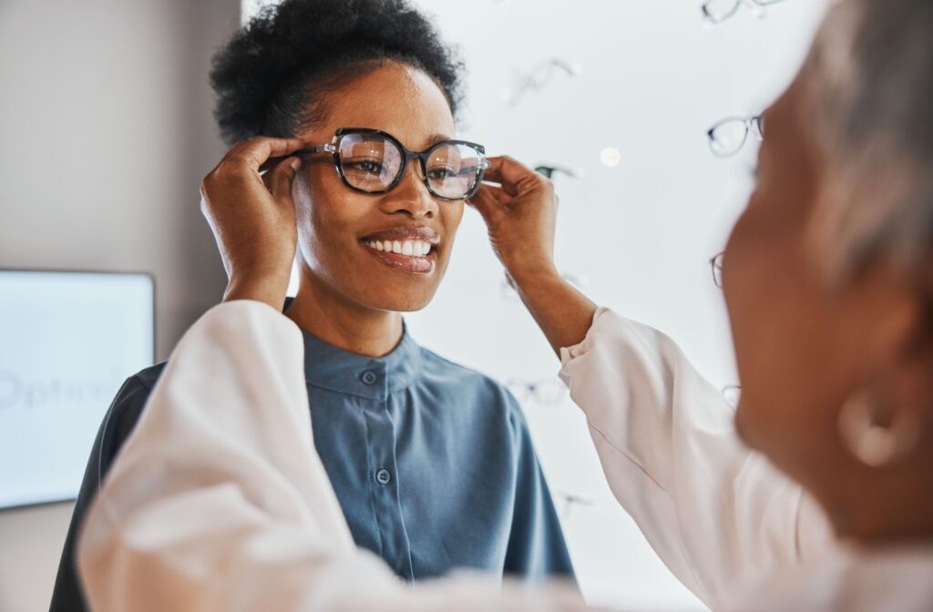 An optometrist helps their patient try on a new pair of sunglasses.