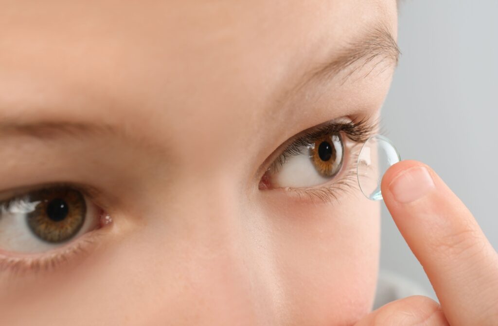a close up of a finger putting a contact lense into an eye