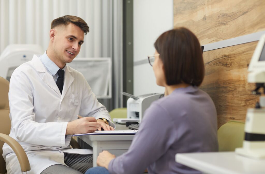 An eye doctor talking to a patient at an optometrist office during an eye exam.