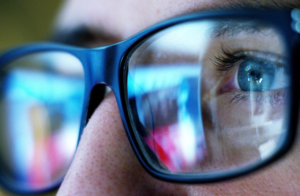 Close up of a person wearing glasses and looking at a computer screen