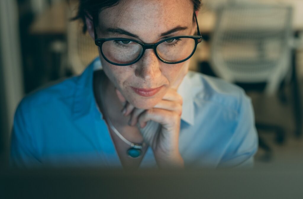 A person wearing glasses as they look at their computer screen